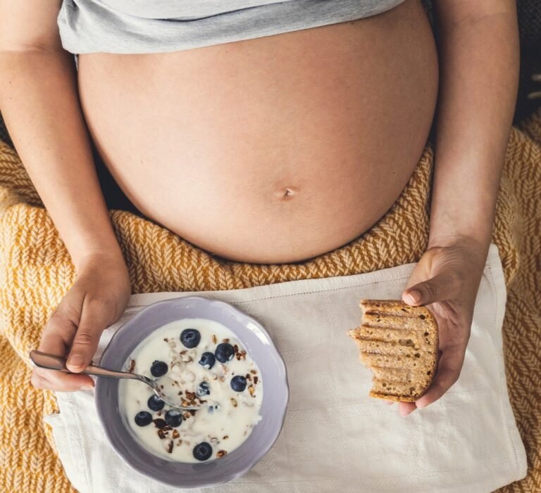 Grávida a comer um iogurte e uma torrada